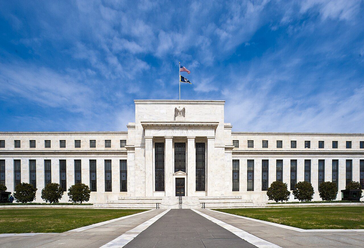 The white marble Eccles Building, headquarters of the US Federal Reserve in Washington, DC, under a blue sky.